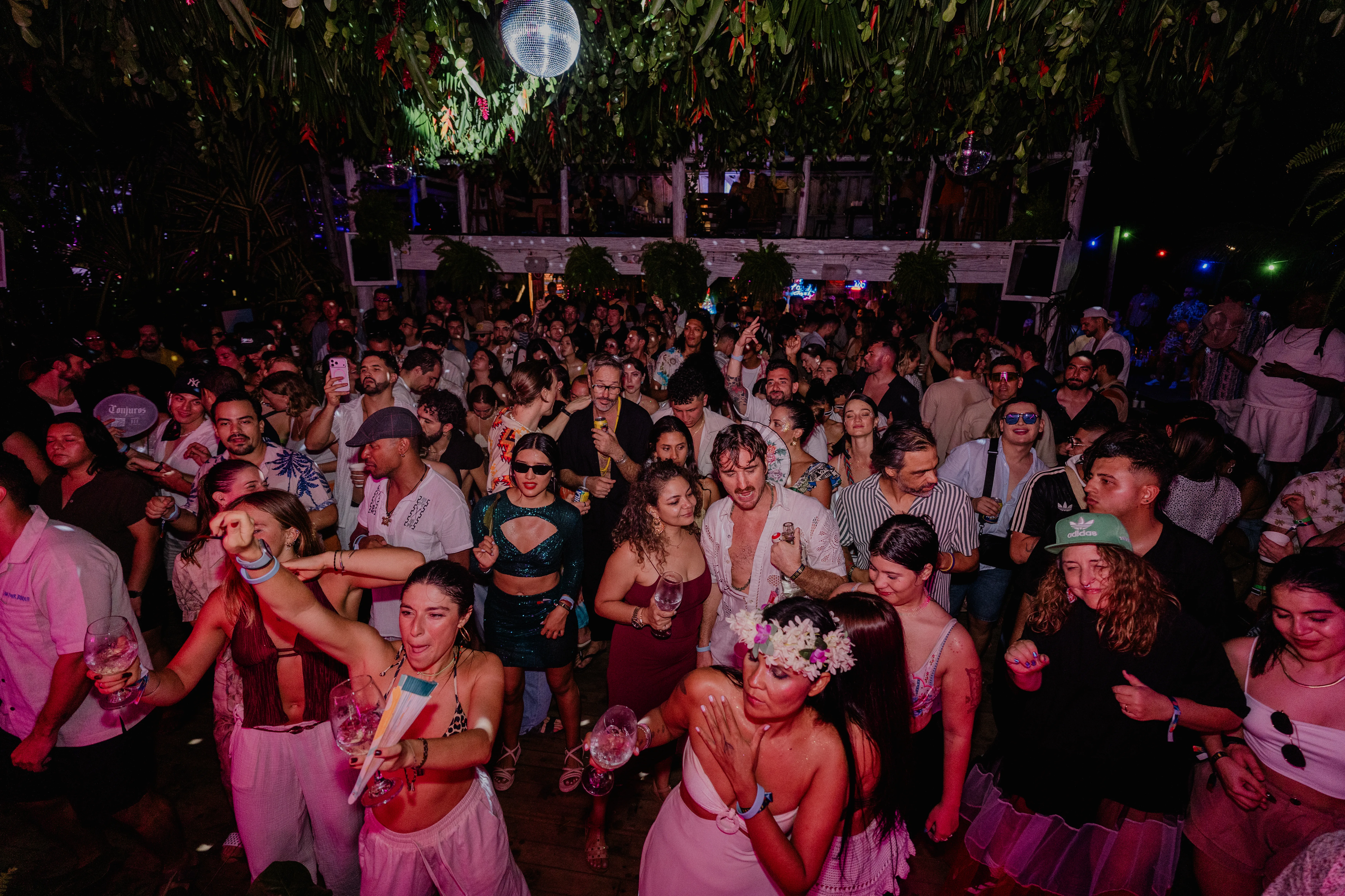 Packed jungle dancefloor under disco ball